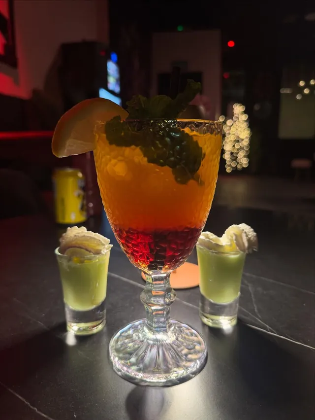 Cóctel con menta y moras junto a dos chupitos con nata