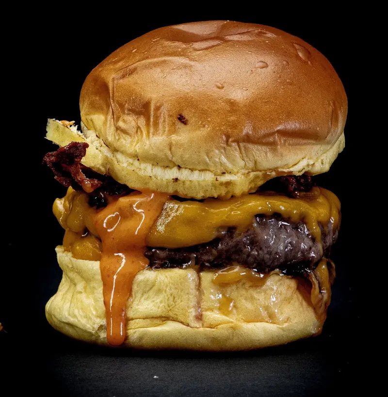 Hamburguesa Bombastic con cheddar fundido, bacon y salsa anaranjada