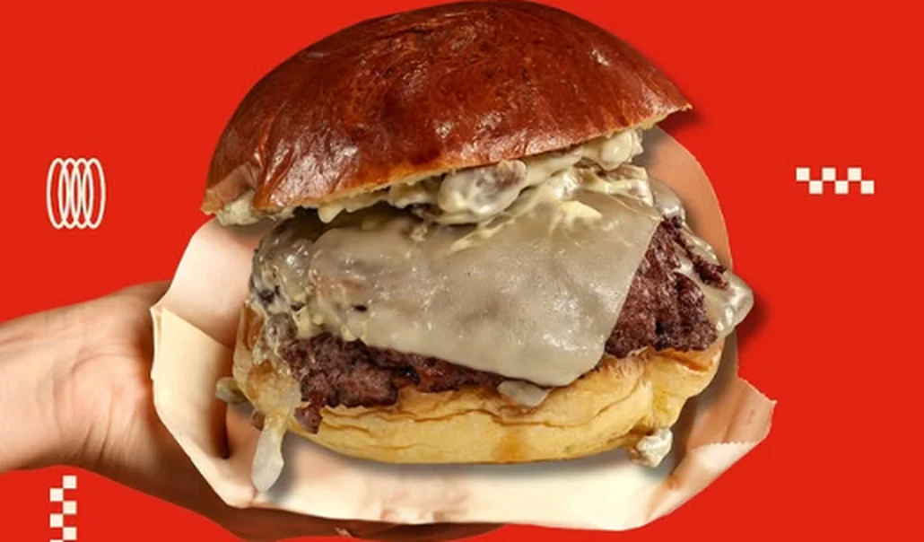 Hamburguesa Della Funghi con queso edam, cebolla y salsa funghi, sostenida con la mano