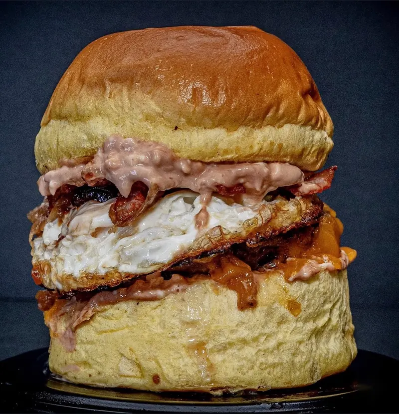 Hamburguesa Della Granja con huevo frito, cheddar fundido, bacon crispy y salsa rosada