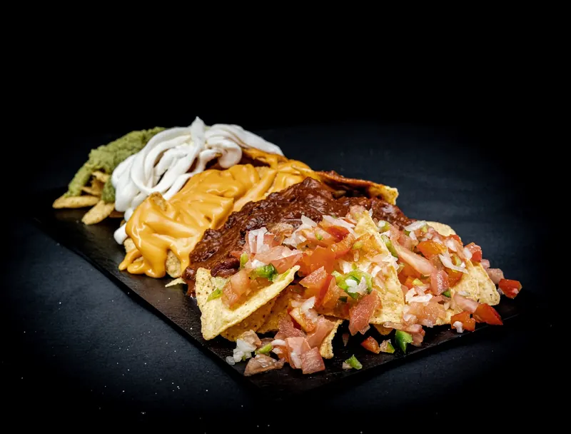 Nachos Della Grotta con salsa cheddar, crema agria, guacamole, chili con carne y pico de gallo
