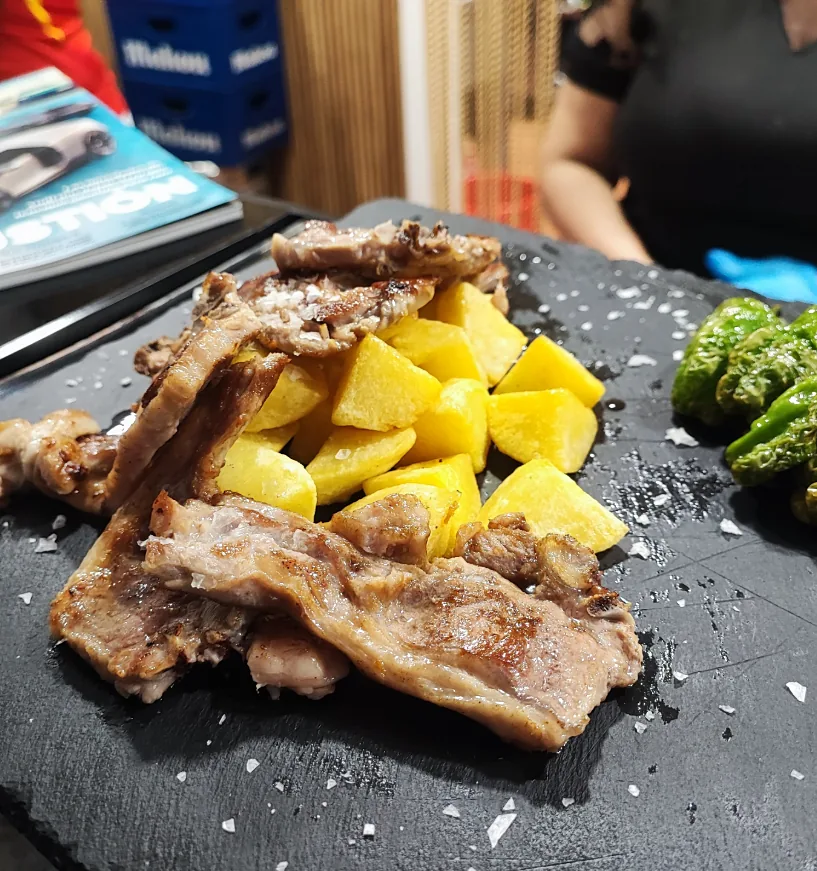 Carne a la plancha con patatas y pimientos verdes sobre una pizarra