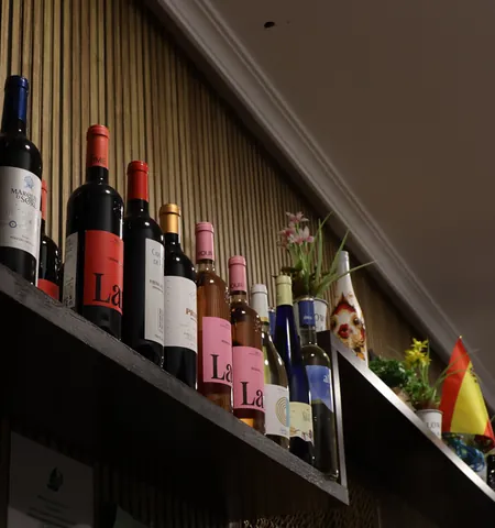Botellas de vino tinto, rosado y blanco en una estantería de madera del bar
